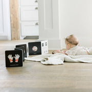 Baby lying on a blanket with educational cards on a wooden floor