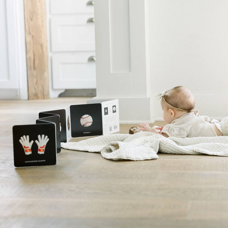 Baby lying on a blanket with educational cards on a wooden floor