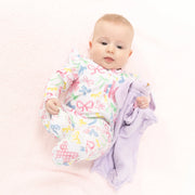 Baby wrapped in a colorful blanket with bow pattern on a white background