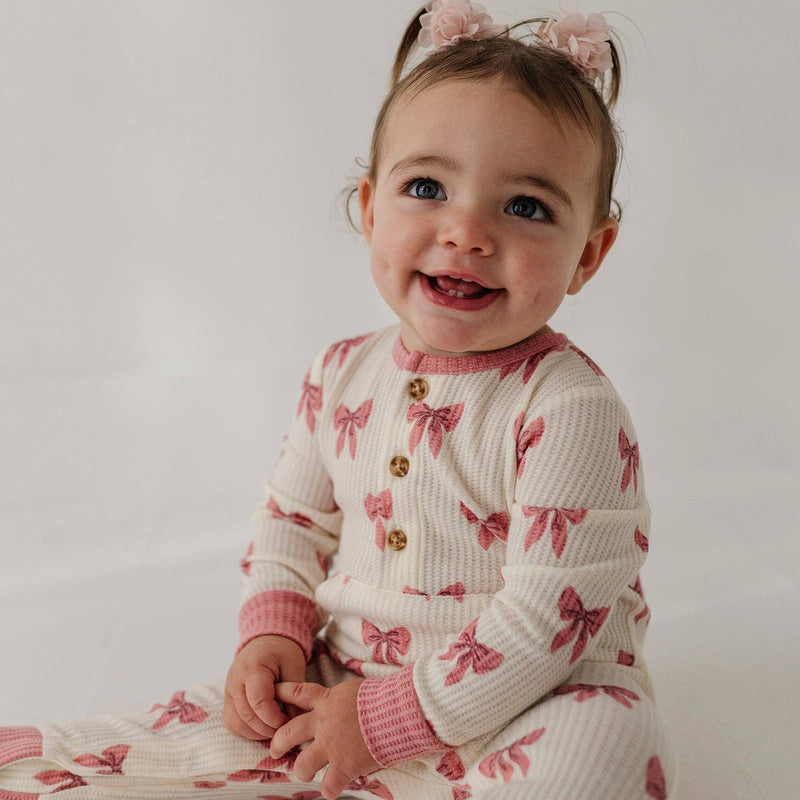 Smiling toddler sitting in the babysprouts Rose Elegance Bows waffle romper