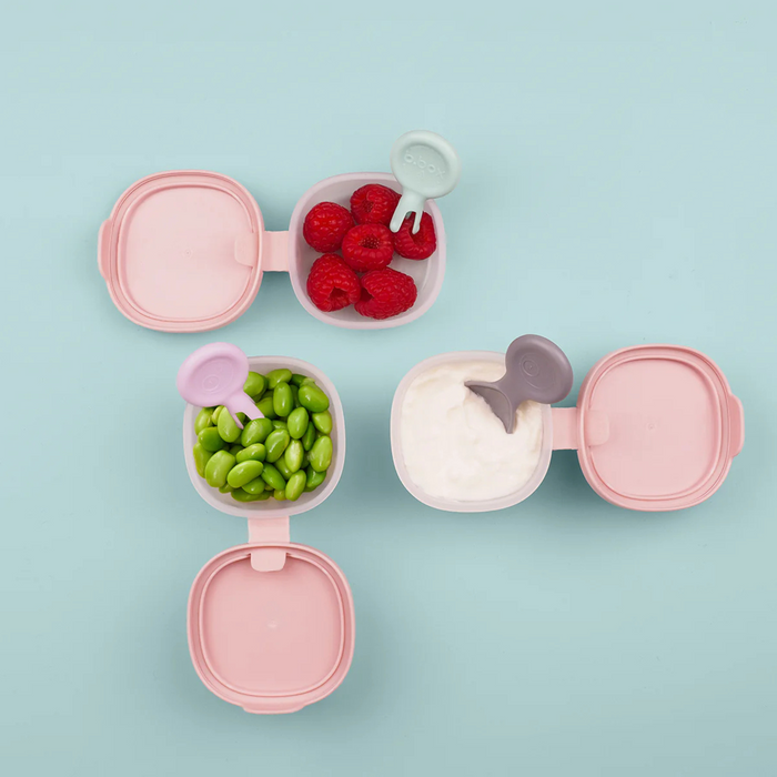 Pink snack containers with food on a light blue background