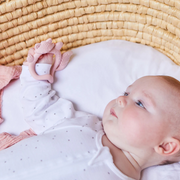 Baby lying on a textured surface with a pink fox silicone teething toy