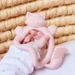 Pink fox-shaped teething ring held by a child's hand against a woven  basket background