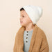 Child wearing as ivory beanie and beige cardigan on a beige background