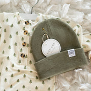 Baby outfit with long-sleeve shirt and green beanie on a textured white surface