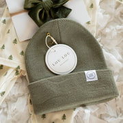 Green beanie with brand tag on a textured white background