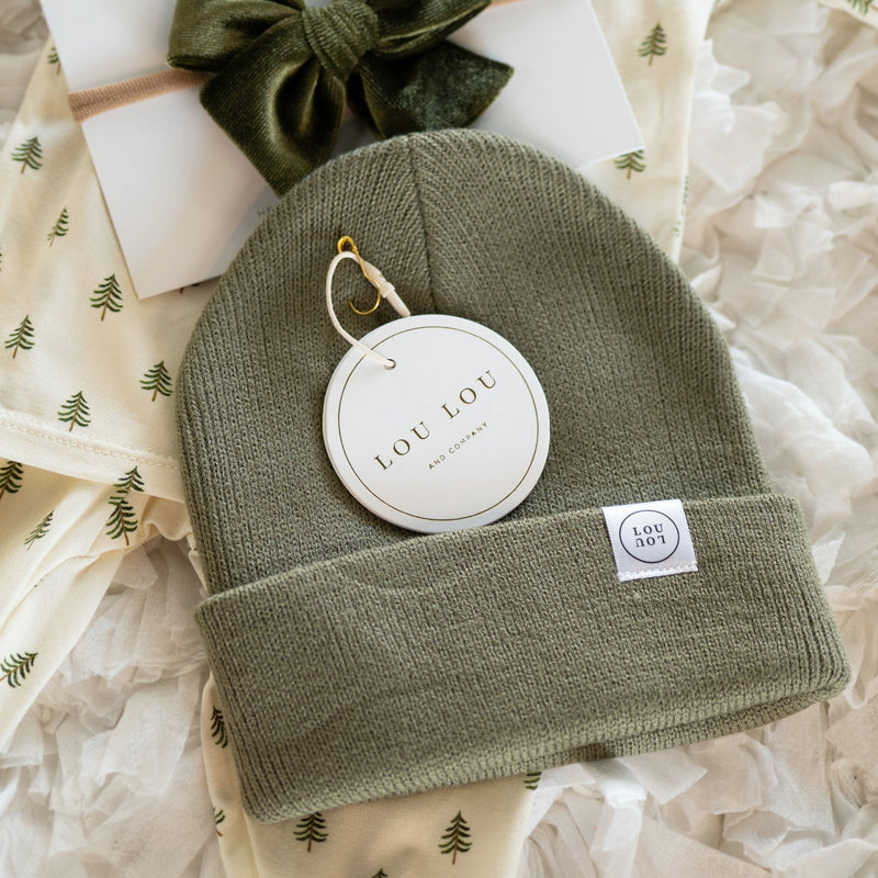 Green beanie with brand tag on a textured white background