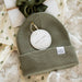 Green beanie with brand tag on a textured white background