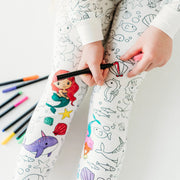 Detail view of child coloring the pajama leg with bright fabric markers