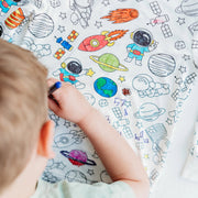 Overhead view of child coloring the space-themed pajama fabric with bright marker designs