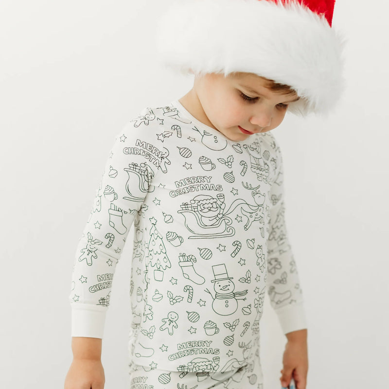 Child wearing Christmas-themed colorable pajamas with holiday illustrations