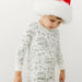 Child wearing Christmas-themed colorable pajamas with holiday illustrations