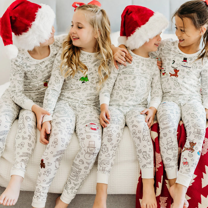 Group of kids sitting together wearing Christmas colorable pajamas and Santa hats