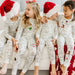 Group of kids sitting together wearing Christmas colorable pajamas and Santa hats