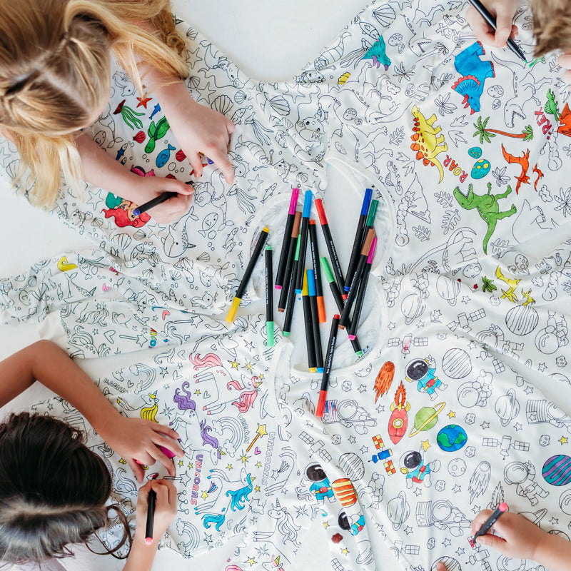 Children coloring pajama designs using fabric markers