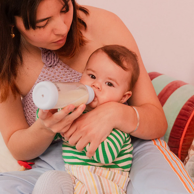Parent feeding a baby with a BIBS glass bottle during a calm feeding moment