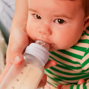 Close-up of baby drinking from a BIBS glass bottle with silicone nipple