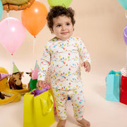 Toddler wearing Birthday Babe magnetic pajamas standing with balloons and gifts