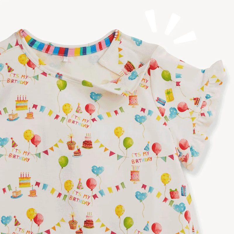 Children's outfit with birthday-themed print on a white background