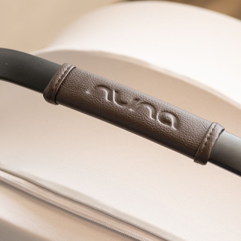 Close-up of a brown leather handle with stitching detail on a beige background