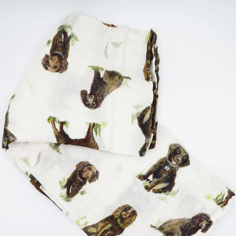 Flatlay of Saltwater Swaddles Boykin Spaniel bamboo cotton swaddle featuring hand-painted watercolor Boykin dogs on white background