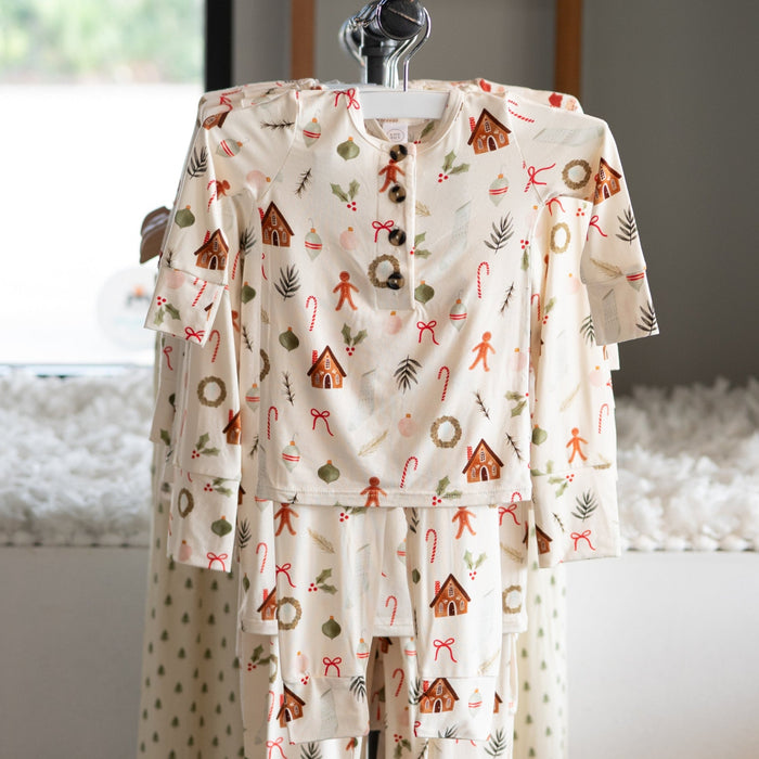 Children's holiday pajama set with gingerbread patterns on a hanger in a room with a window 