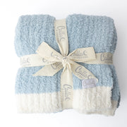 Folded blue and white blanket with a decorative bow and 'Calla' branding on a white background