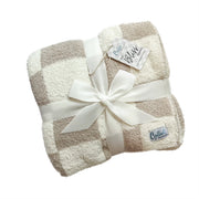 Fawn and cream checkered plush blanket folded with ribbon and brand tags