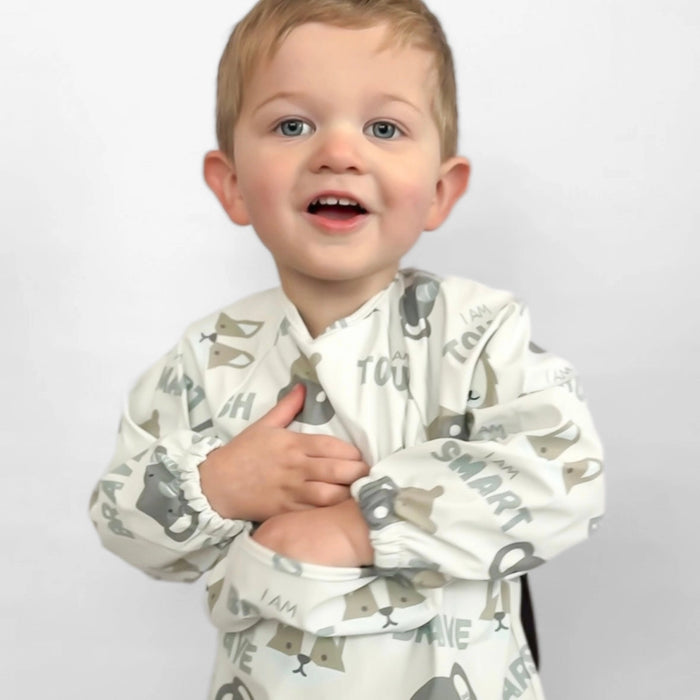Child wearing a white shirt with gray text and animal prints on a plain background
