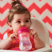 Child in a high chair with a pink sippy cup against a red and white chevron background
