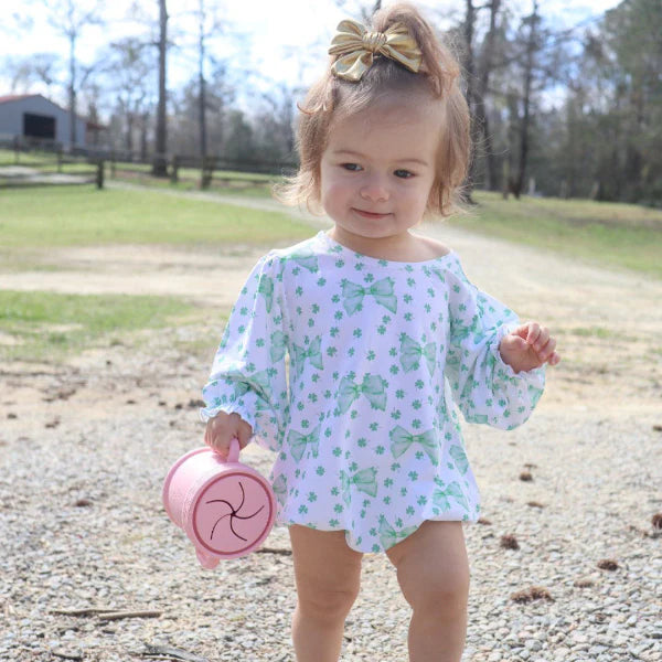 A toddler in a light patterned romper holds the pink Coastal Cup outdoors, showing its easy-to-carry double handle design.