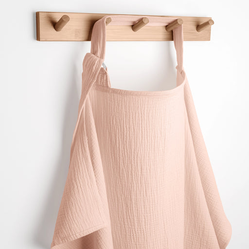 Blush apron hanging on a wooden rack against a white background