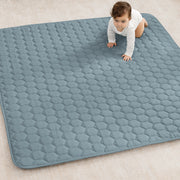 Baby crawling on a large blue quilted mat