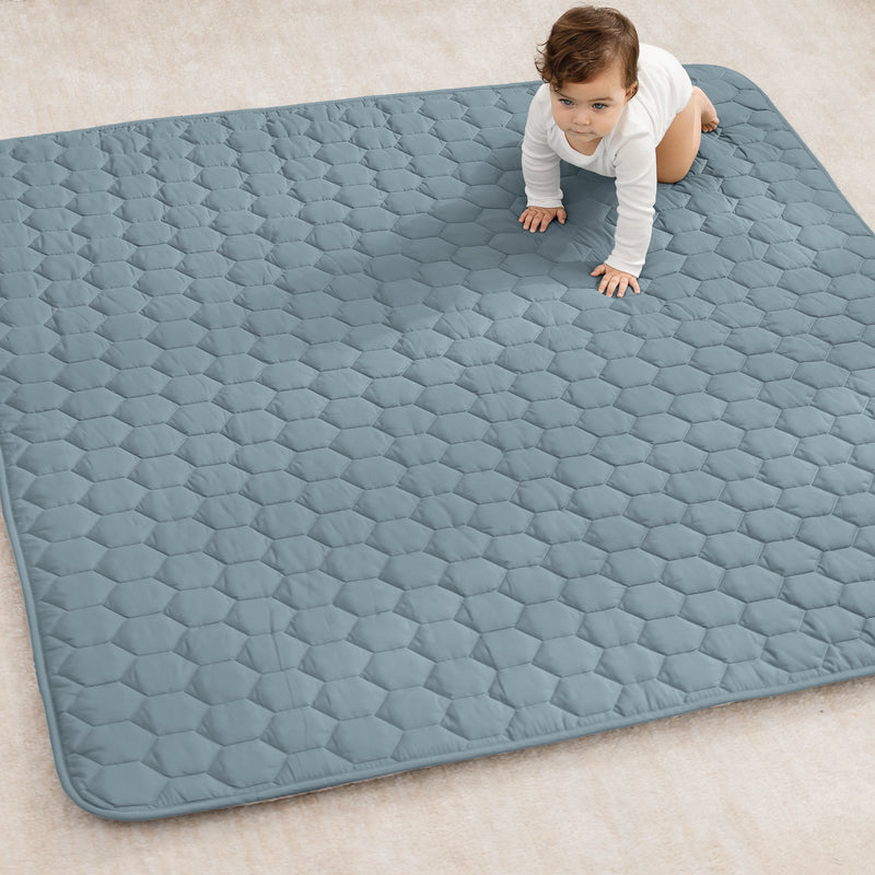 Baby crawling on a large blue quilted mat