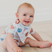 Baby sitting on the floor wearing the baseball pinstripe Copper Pearl All Star bandana bib