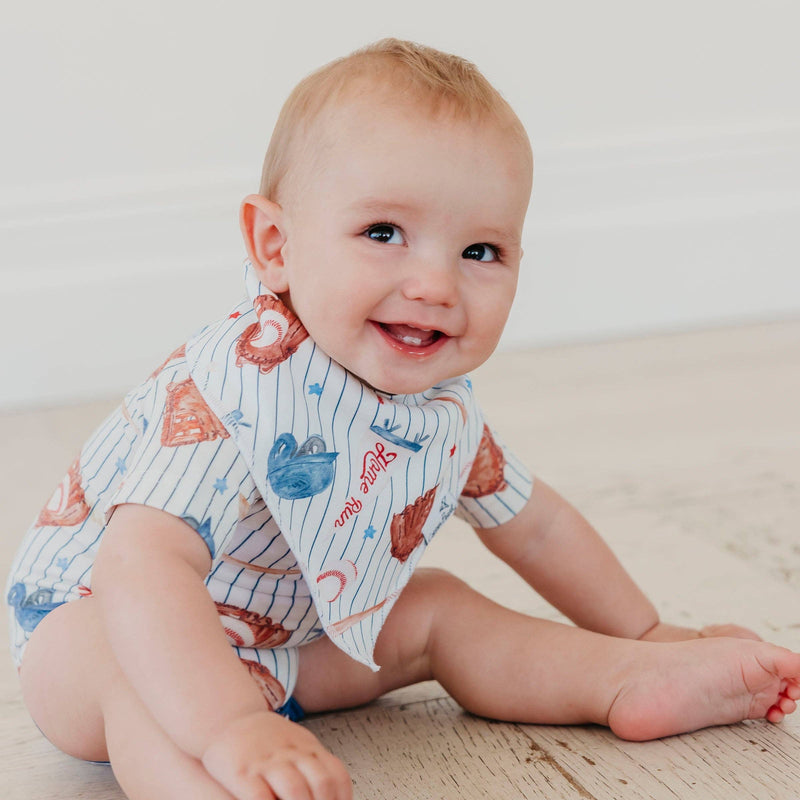 Baby sitting on the floor wearing the baseball pinstripe Copper Pearl All Star bandana bib