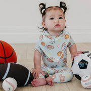 Baby seated with a football, basketball and soccer ball wearing a Copper Pearl All Star bandana bib