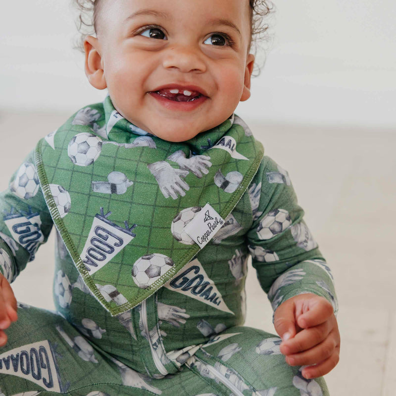 Baby sitting and smiling in the green soccer Copper Pearl All Star bandana bib