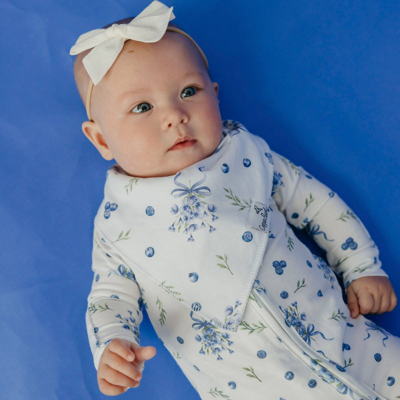 Baby in matching pajamas wearing the blue floral Copper Pearl Catherine bandana bib