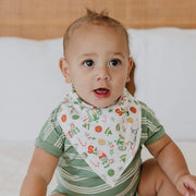Baby sitting and wearing white wreath print Copper Pearl bandana bib