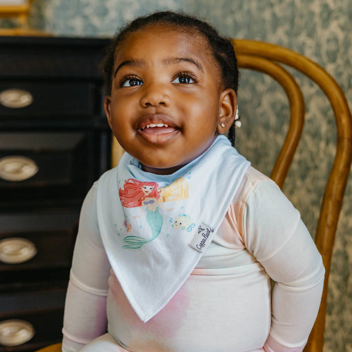 Baby wearing lavender outfit and Copper Pearl bandana bib featuring Ariel and friends