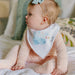 Baby in profile wearing Copper Pearl bandana bib with Cinderella carriage print