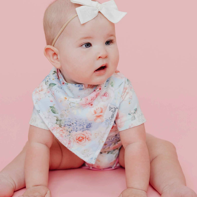 Baby glancing sideways while wearing a floral Copper Pearl Genevieve bandana bib
