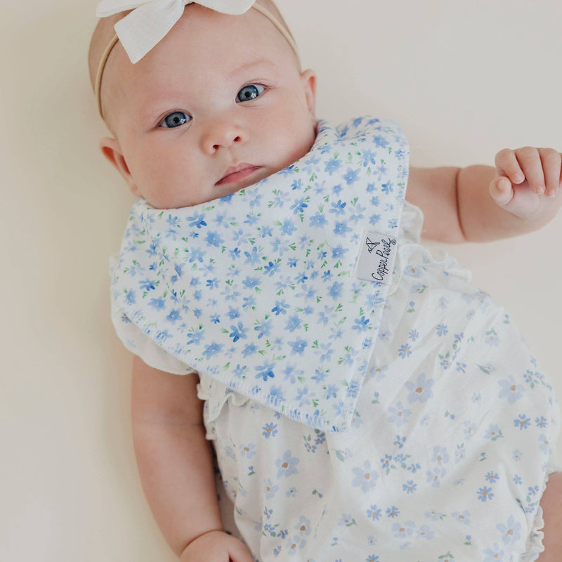 Baby lying down wearing the blue floral Copper Pearl Genevieve bandana bib