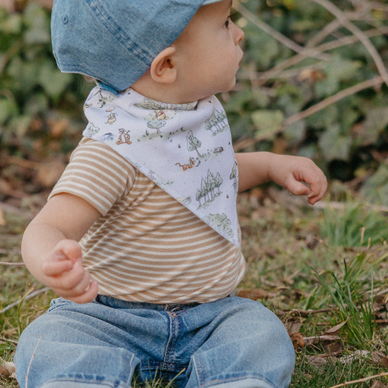 Toddler wearing a Copper Pearl Hundred Acre Wood Winnie the Pooh bandana bib outdoors