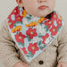 Baby wearing a floral bib with a beige sweater