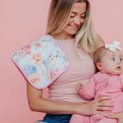 Woman holding a baby with a floral Copper Pearl Genevieve burp cloth over her shoulder