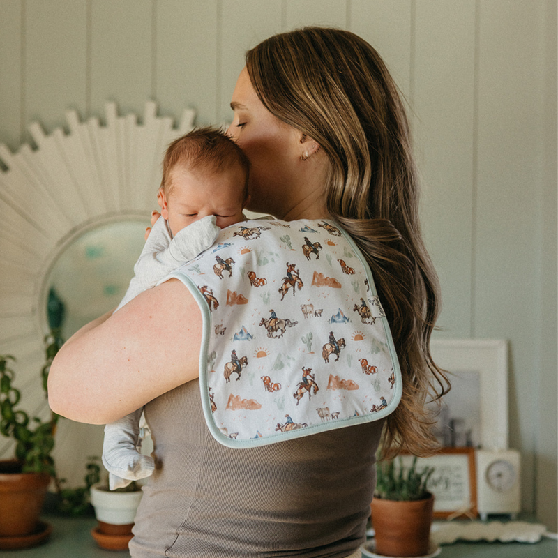Parent holding baby with a Copper Pearl Boone burp cloth in cowboy print over the shoulder