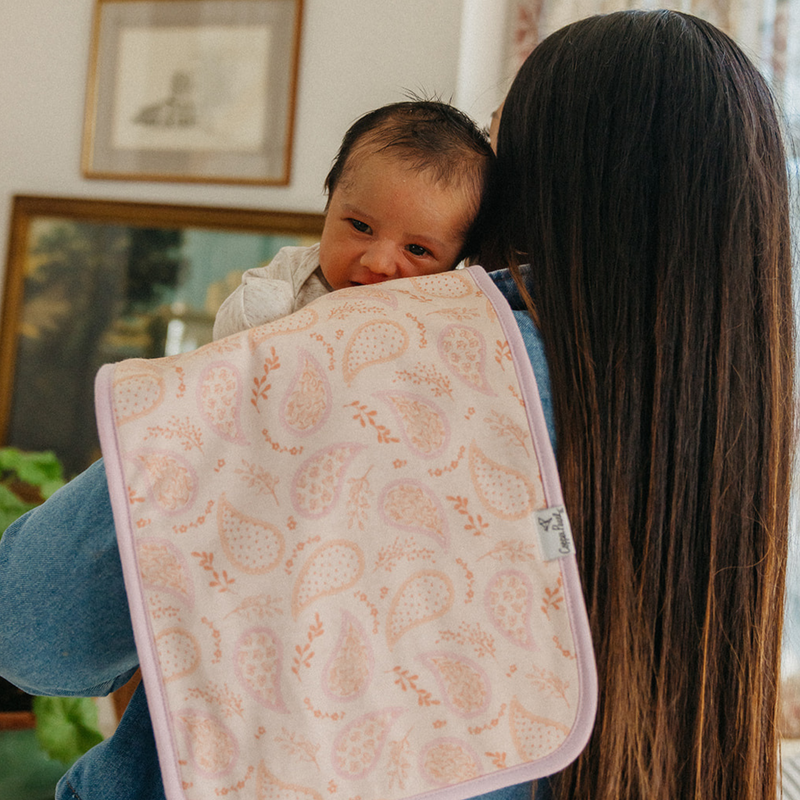 Parent holding baby with a Copper Pearl Cheyenne burp cloth in pink print over the shoulder