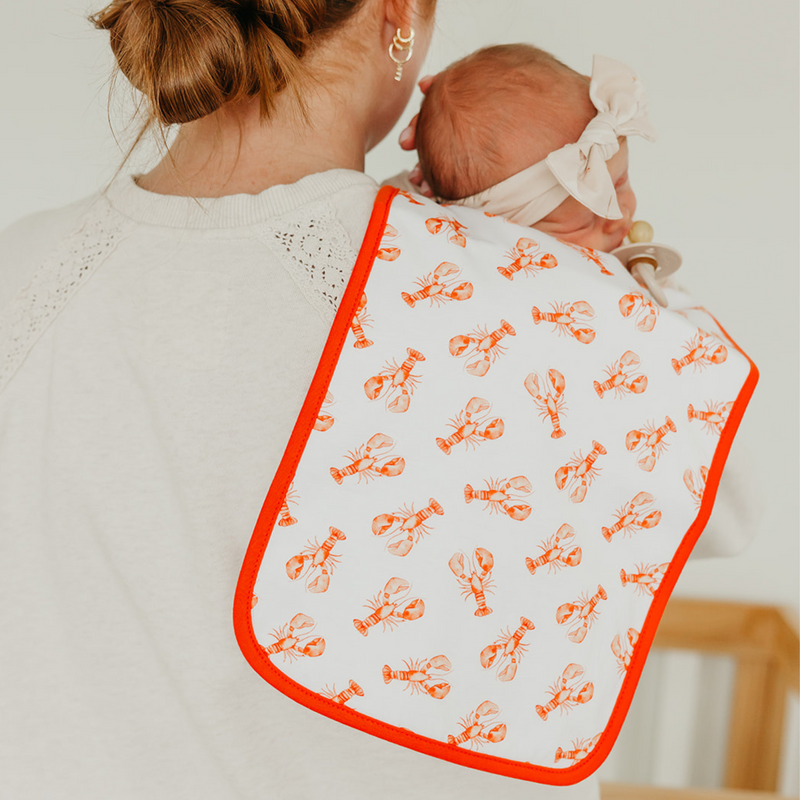 Parent holding baby with a Copper Pearl Fischer burp cloth in lobster print over the shoulder